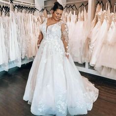 a woman standing in front of wedding dresses