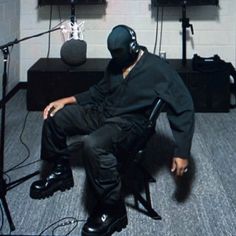 a man sitting in a chair with headphones on his ears and wearing a black mask