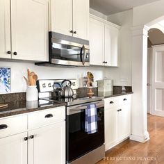 a kitchen with white cabinets and black appliances