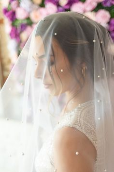 a woman wearing a wedding veil in front of flowers