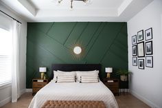 a bedroom with green walls and pictures on the wall above the bed, along with a bench