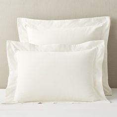 two white pillows sitting next to each other on a bed