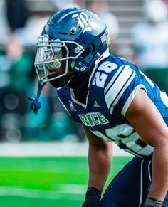 a football player kneeling on the field with his hands in his pockets and wearing a helmet