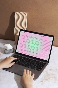 a person using a laptop computer on a marble table with other items in the background