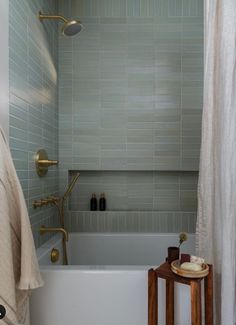 a bath tub sitting next to a wooden stool under a shower curtain in a bathroom