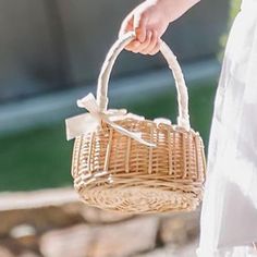 a person holding a wicker basket with a bow on the handle and white dress