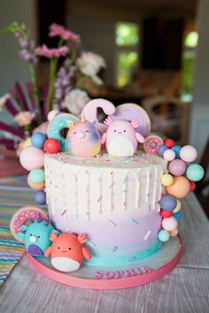 there is a cake decorated with balloons and animals on the top it sits on a table