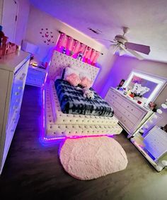 a bedroom decorated in pink and white with a bed that has lights on the headboard