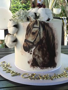 a white cake with a horse on it's face and flowers in the middle