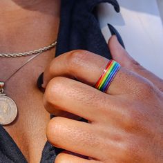 a person wearing a rainbow colored ring with a coin on their left hand and a chain around his neck