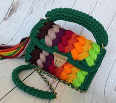 a multicolored handbag is sitting on a white wooden floor with a tassel