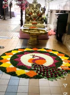 a large flower arrangement on the ground in front of a statue