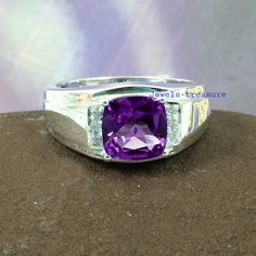 an amethyst purple stone is set in a white gold and silver ring on top of a rock