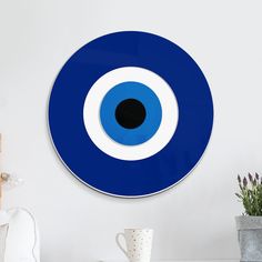 a blue clock with an evil eye on the front of it's face is next to a potted plant