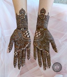 two hands with henna tattoos on them, one is showing the intricate pattern and the other has an elaborate design