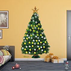 a christmas tree decorated with yellow and white ornaments in a room next to a bed