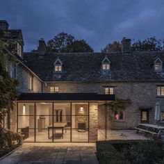 a house that is lit up at night with lights on the windows and patio area