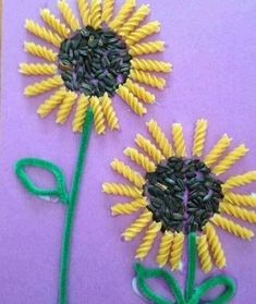 two sunflowers made out of pasta on purple paper