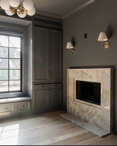 an empty room with gray cabinets and a fireplace in the center, surrounded by two lamps