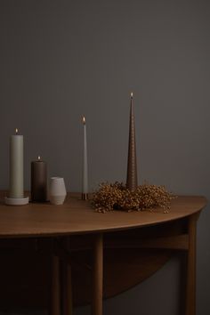 three candles on a table with some flowers and other things in front of the table