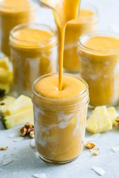 a jar filled with yellow liquid next to sliced pineapples