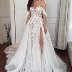 a woman wearing a white wedding gown with an off the shoulder top and thigh high slit