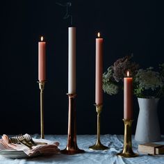 three candles are lit on a table with plates and napkins