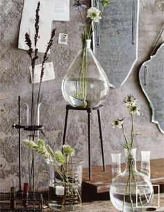 three vases with flowers in them sitting on a table next to a mirror and other items