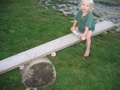 a little boy sitting on top of a wooden bench in the grass next to a fire hydrant