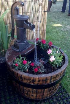 a wooden barrel filled with flowers next to a water faucet