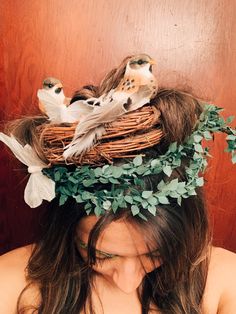 a woman with long hair wearing a bird nest on her head