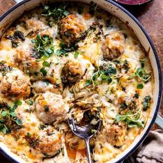 a casserole with meatballs, cheese and herbs in a skillet on a wooden table