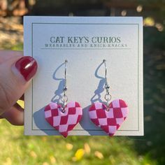 a pair of pink and white checkered heart shaped earrings on top of a card