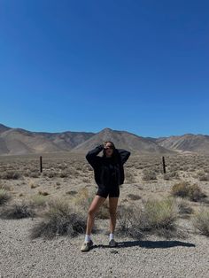 a woman is standing in the desert with her hands on her head