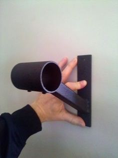 a person is holding up a cup on a wall with a black holder attached to it