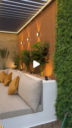 a couch sitting on top of a white bench next to a green plant covered wall