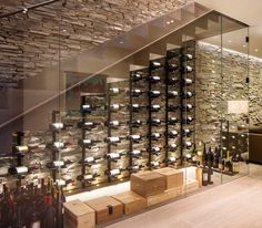 a wine cellar filled with lots of bottles next to a wall covered in glass shelves