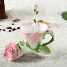 a pink rose sitting on top of a saucer next to a coffee cup and beans