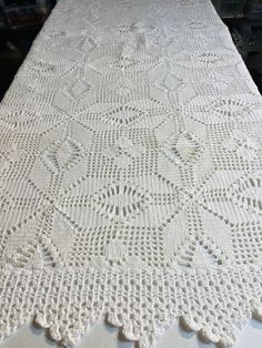 a white crocheted tablecloth on top of a wooden table