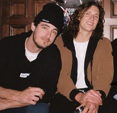 three young men sitting next to each other in front of a poster on the wall