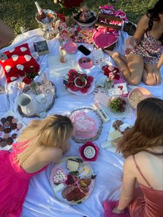 two women sitting at a table with cakes and desserts on it, all dressed in pink