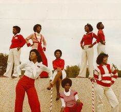 a group of women standing next to each other on top of a cement wall with candy canes in front of them