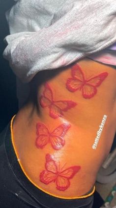 a woman's back with red butterflies painted on her stomach and the bottom part of her body