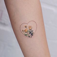 a small heart shaped tattoo with roses on the inside of it's left arm