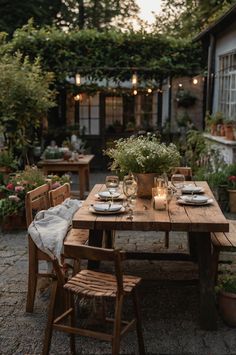 a wooden table with plates and glasses on it in the middle of an outdoor patio