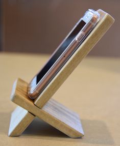 a cell phone is sitting in a wooden holder on a table top with a wood base