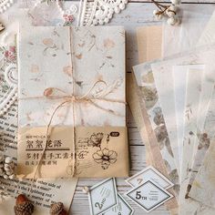 several pieces of paper are laid out on a table with lace, pine cones and twine