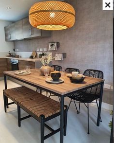 a dining table with two chairs and a bench under a light fixture in a kitchen