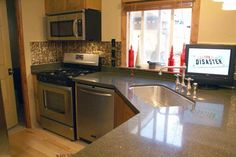 a kitchen with stainless steel appliances and granite counter tops, along with a television mounted on the wall