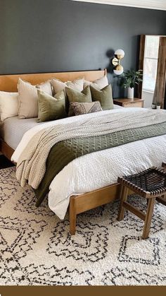 a large bed sitting in a bedroom on top of a white and green rug next to a window